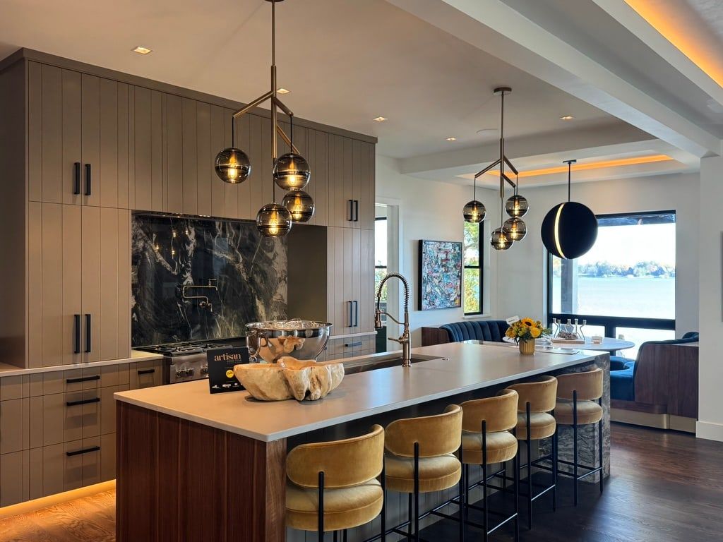 Kitchen with a large island, dark stone backsplash, pendant lights and adjoining dining area.