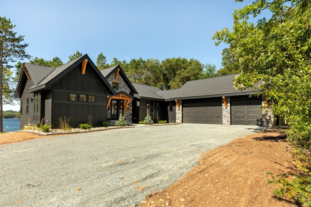Front exterior with dark siding, stone entry and attached three-car garage