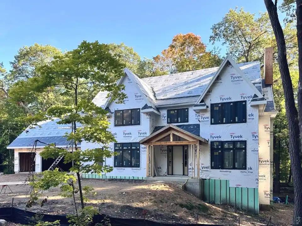 A two-storey house framed and house-wrapped, its roof sheathed and its windows in