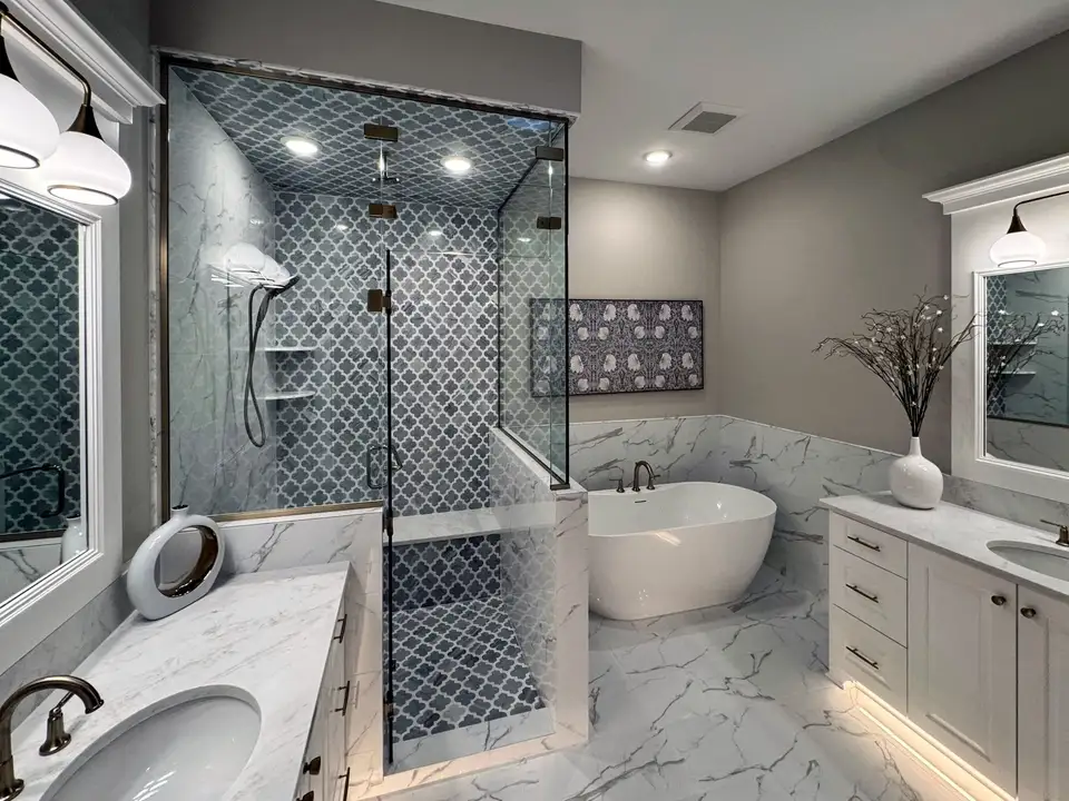 A primary bath with a glass steam shower in grey arabesque tile beside a freestanding tub