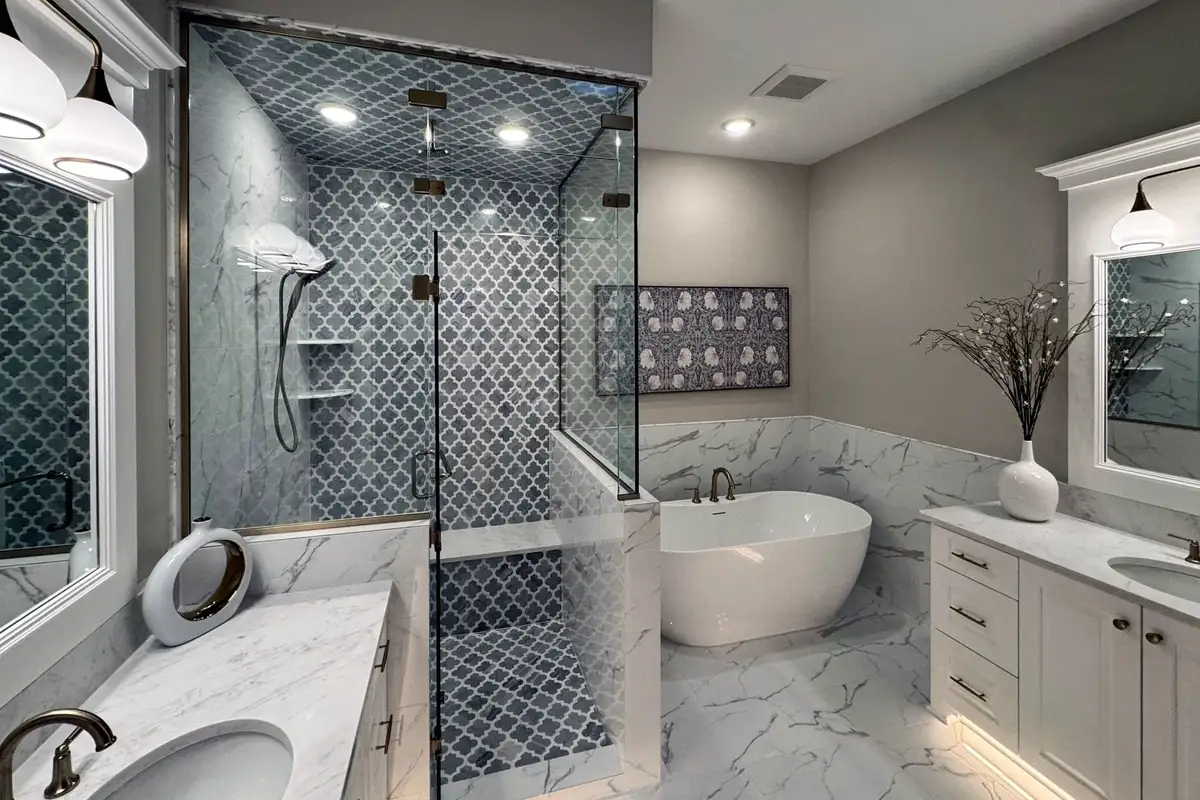 The primary bath of the Ron Clark Construction model in Eden Prairie: a glass steam shower in grey arabesque tile beside a freestanding tub and white vanities