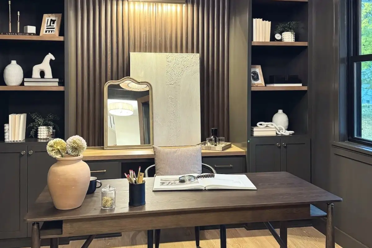 A home office of dark built-in shelving around a fluted wall and a walnut desk, in the Craft Homes model in Edina
