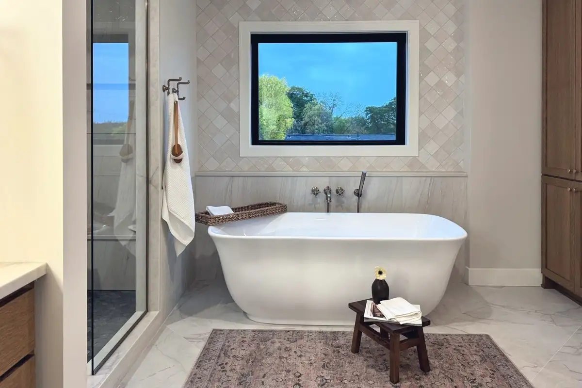 A freestanding tub under a window set in zellige tile, in the Craft Homes model in Edina