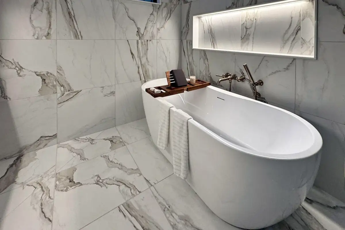 A freestanding tub in the TJB Homes model in Edina, below a lit tile niche and a window to the trees
