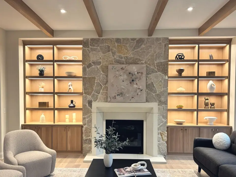A great room with a stone fireplace between lit oak built-ins