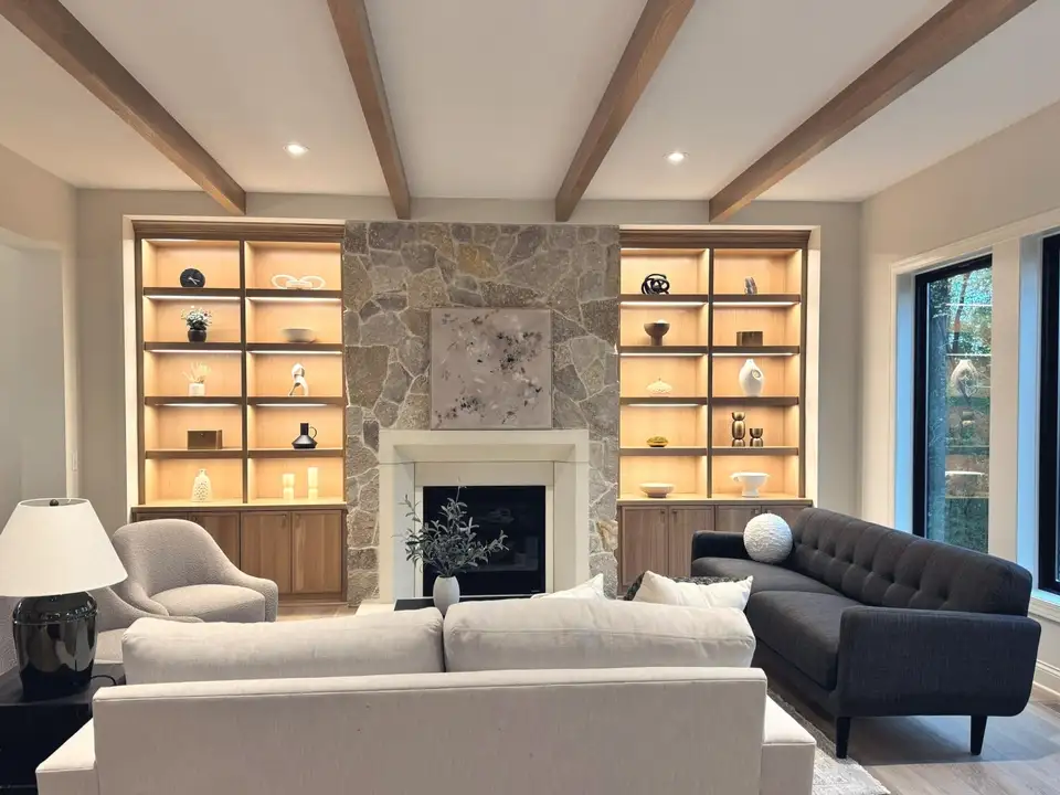 A furnished great room with a stone fireplace and tall windows