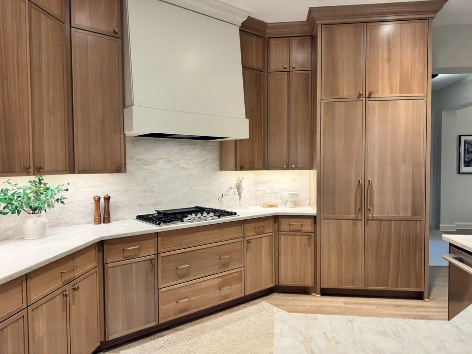 The corner of an oak kitchen with a tall pantry wall and a plaster hood