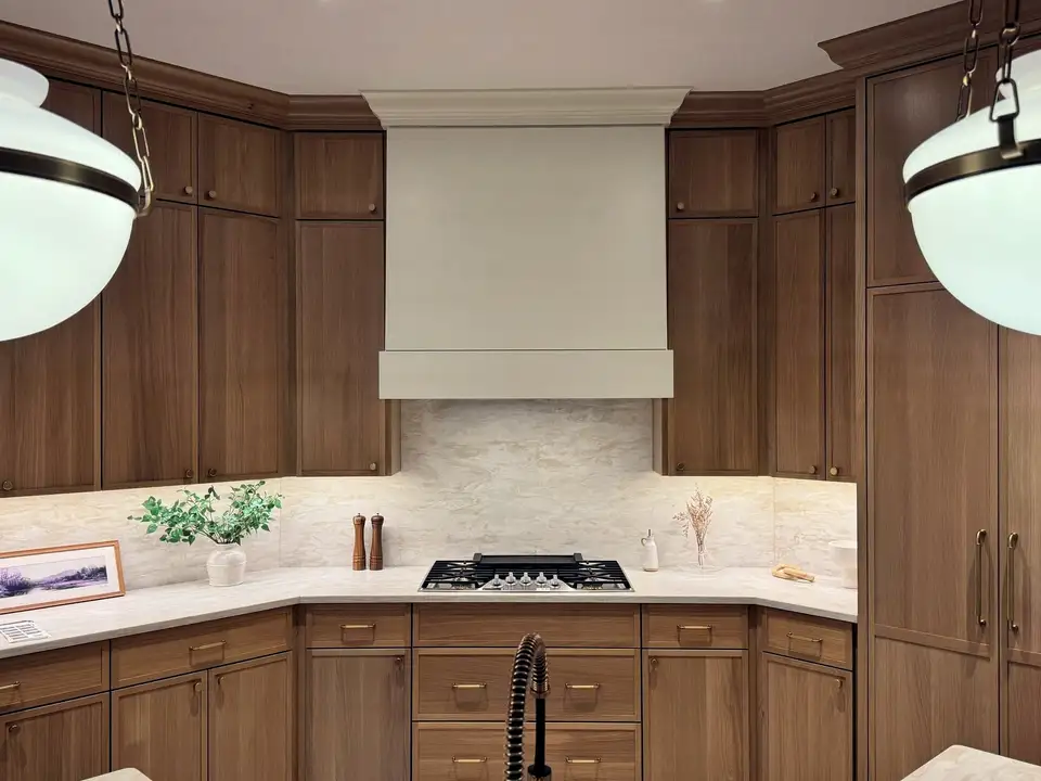 A kitchen of warm oak cabinetry around a plaster range hood