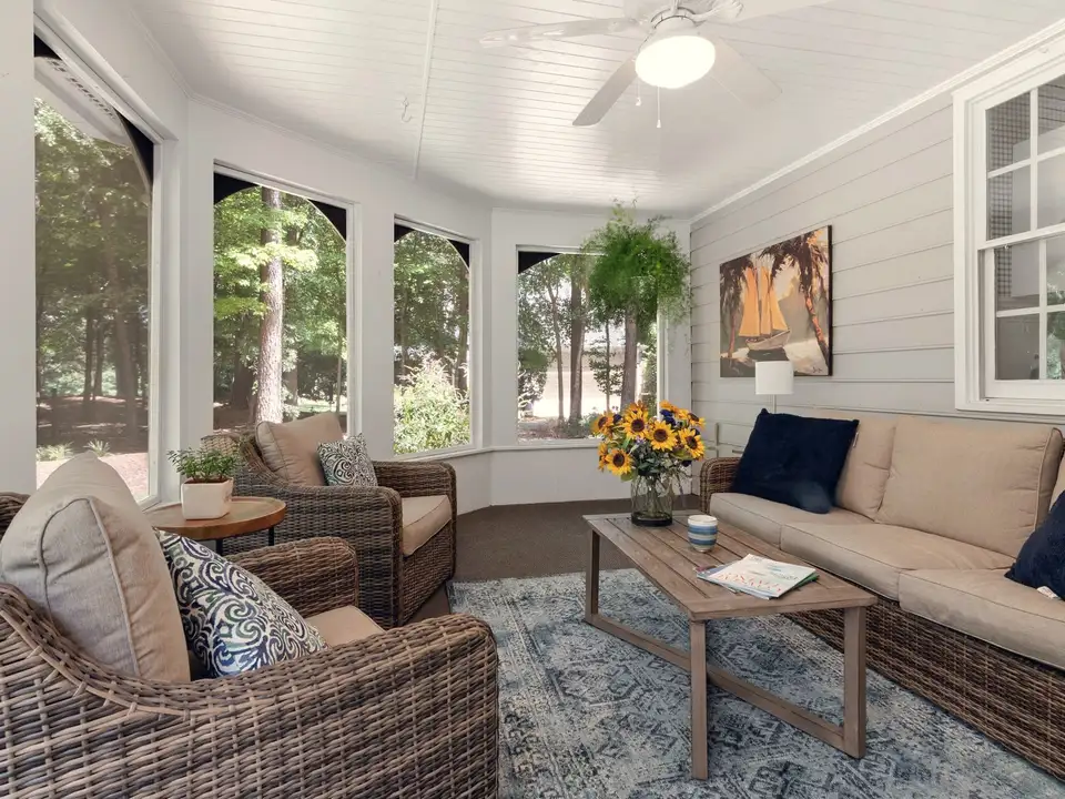 A sunroom addition with windows on three sides, furnished