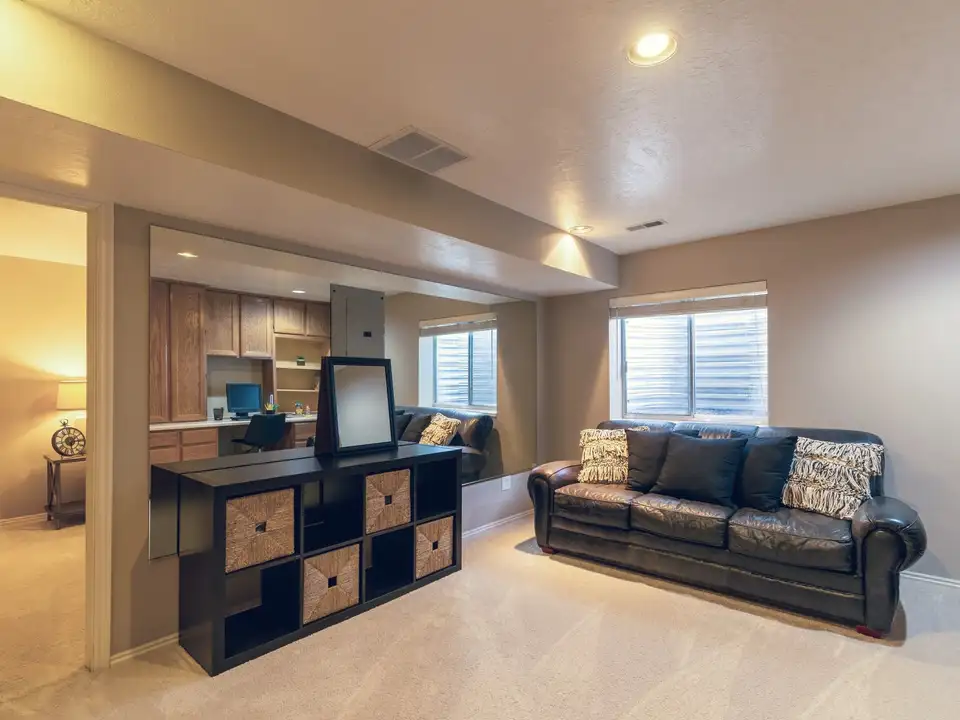 A finished lower-level family room with a leather sofa
