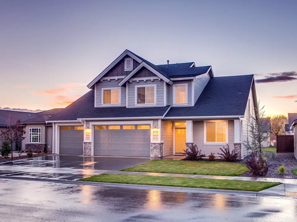 A two-storey craftsman-style home at dusk, its windows lit