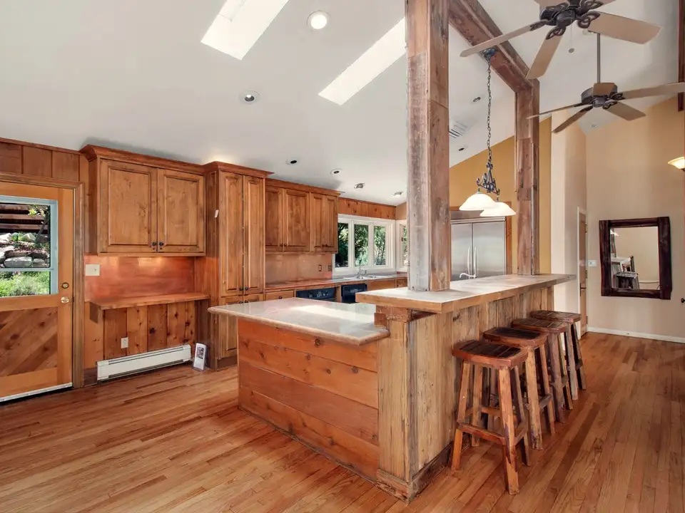 A timber-beamed kitchen with a wood island and skylights