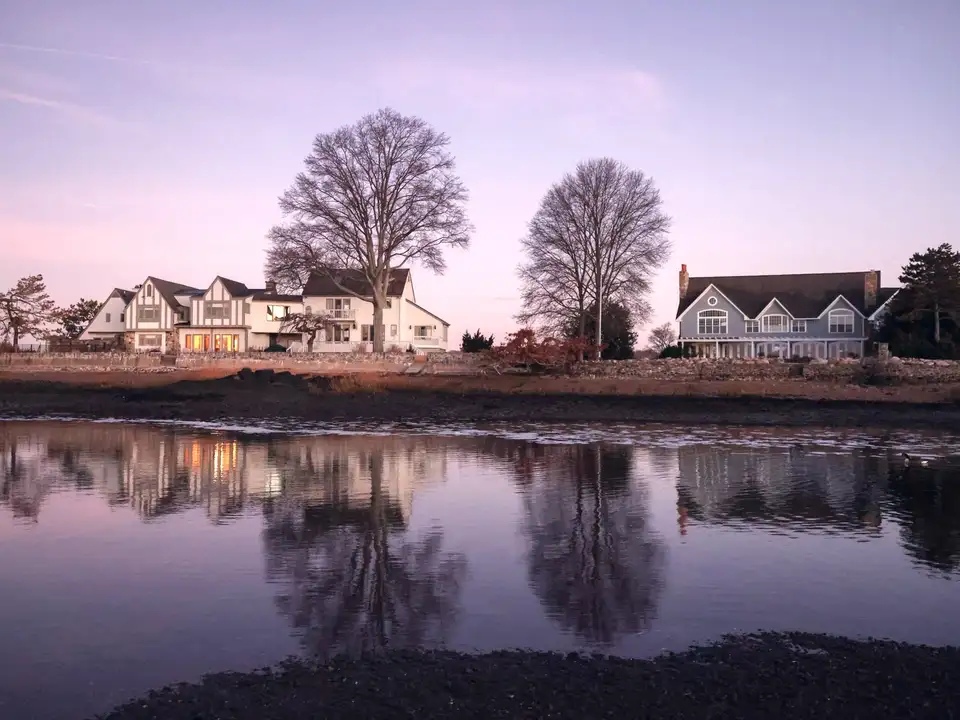 Shoreline homes at dusk reflected in still water