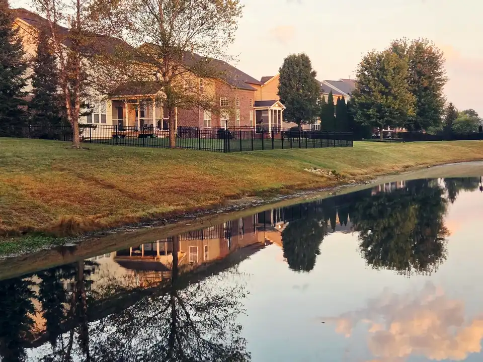 Suburban homes along a pond in autumn, reflected in the water