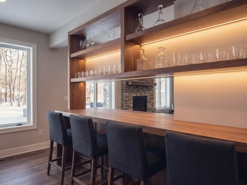 A lower-level bar with stools and wood shelving
