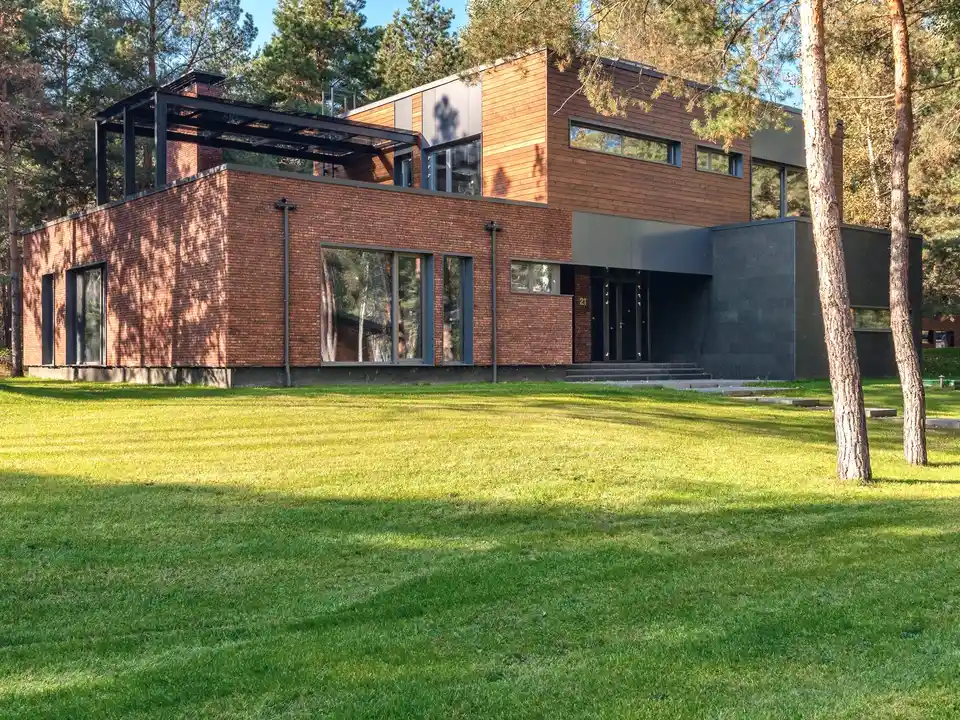 A modern brick and timber home among pines, across a mown lawn