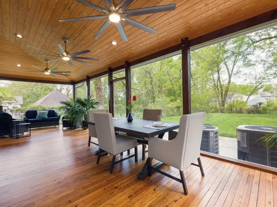 A screened porch with a dining table, looking out into trees