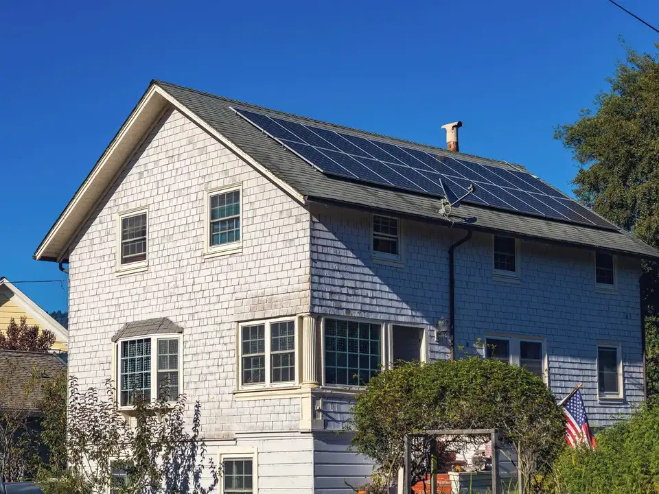 A white shingled house with solar panels on its roof